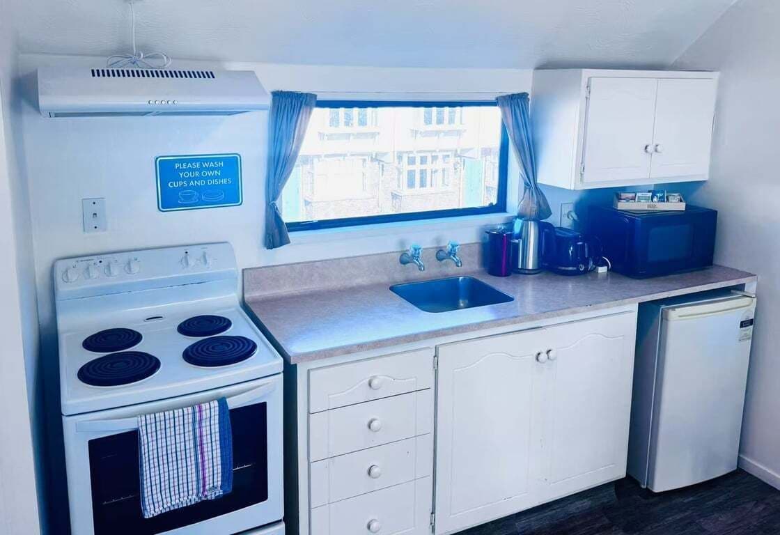 A compact kitchenette with a stove, sink, and cabinets.