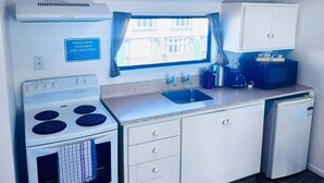 A compact kitchenette with a stove, sink, and cabinets.