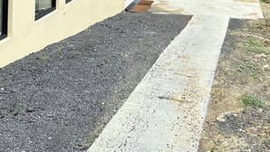 Un bâtiment au design moderne, caractérisé par une combinaison de façades sombres et claires, de nombreuses fenêtres et un espace d’entrée pavé.