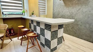 Une cuisine avec un dosseret à carreaux, des tabourets en bois et un bar intégré.