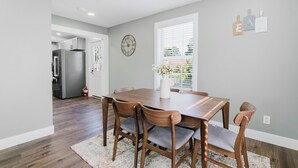 Un comedor con una mesa y sillas de madera, un florero con flores y un reloj en la pared.
