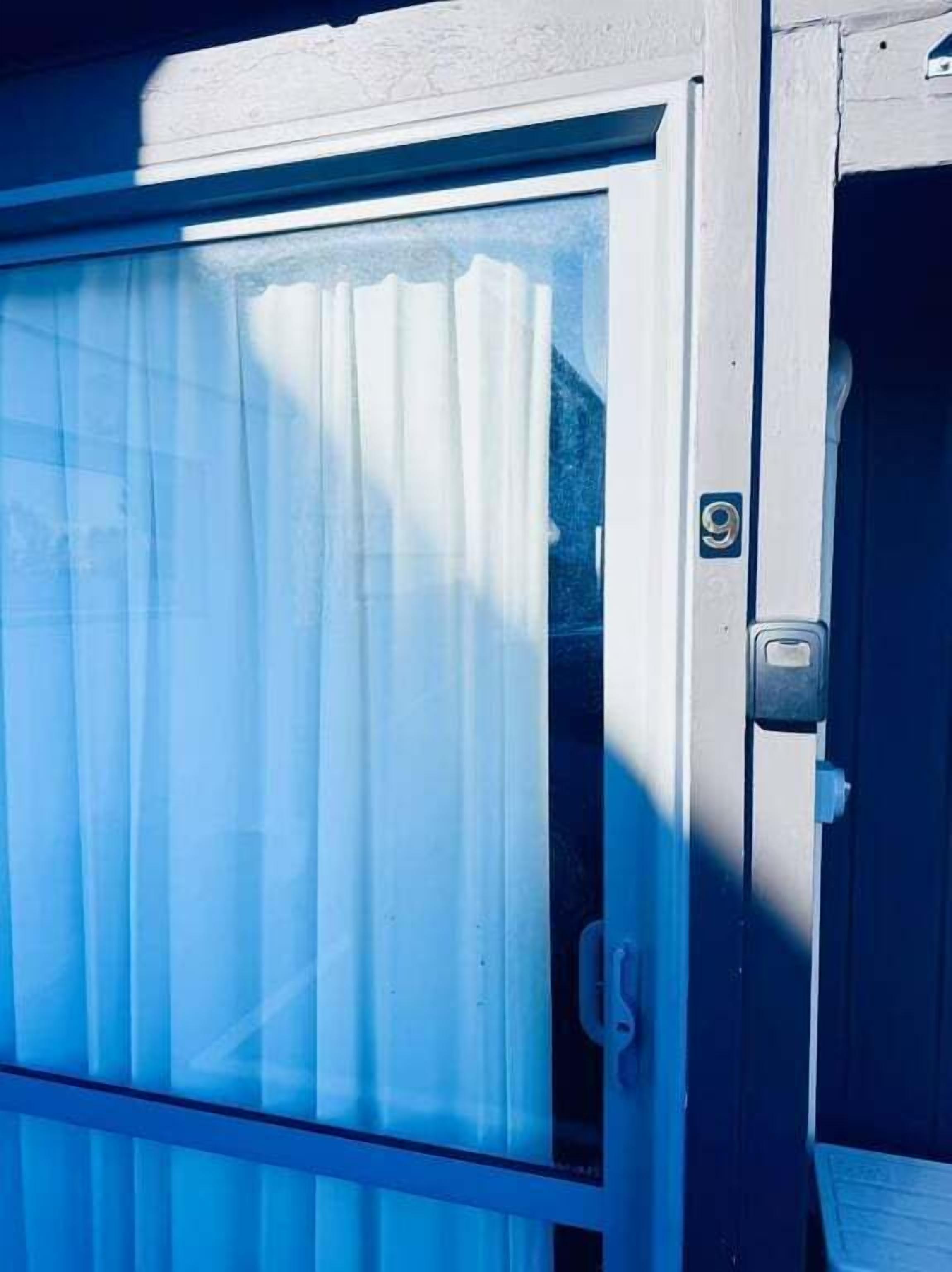 A door with a white curtain, a visible lock, and a small window.