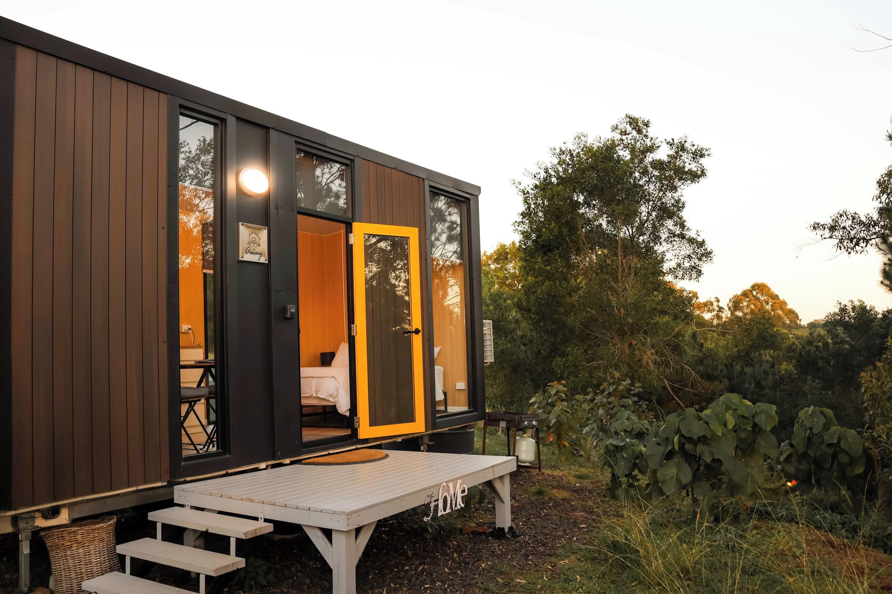 Una cabaña moderna con fachada de madera, un banco y una mesa en el exterior.