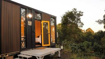 Una cabaña moderna con fachada de madera, un banco y una mesa en el exterior.