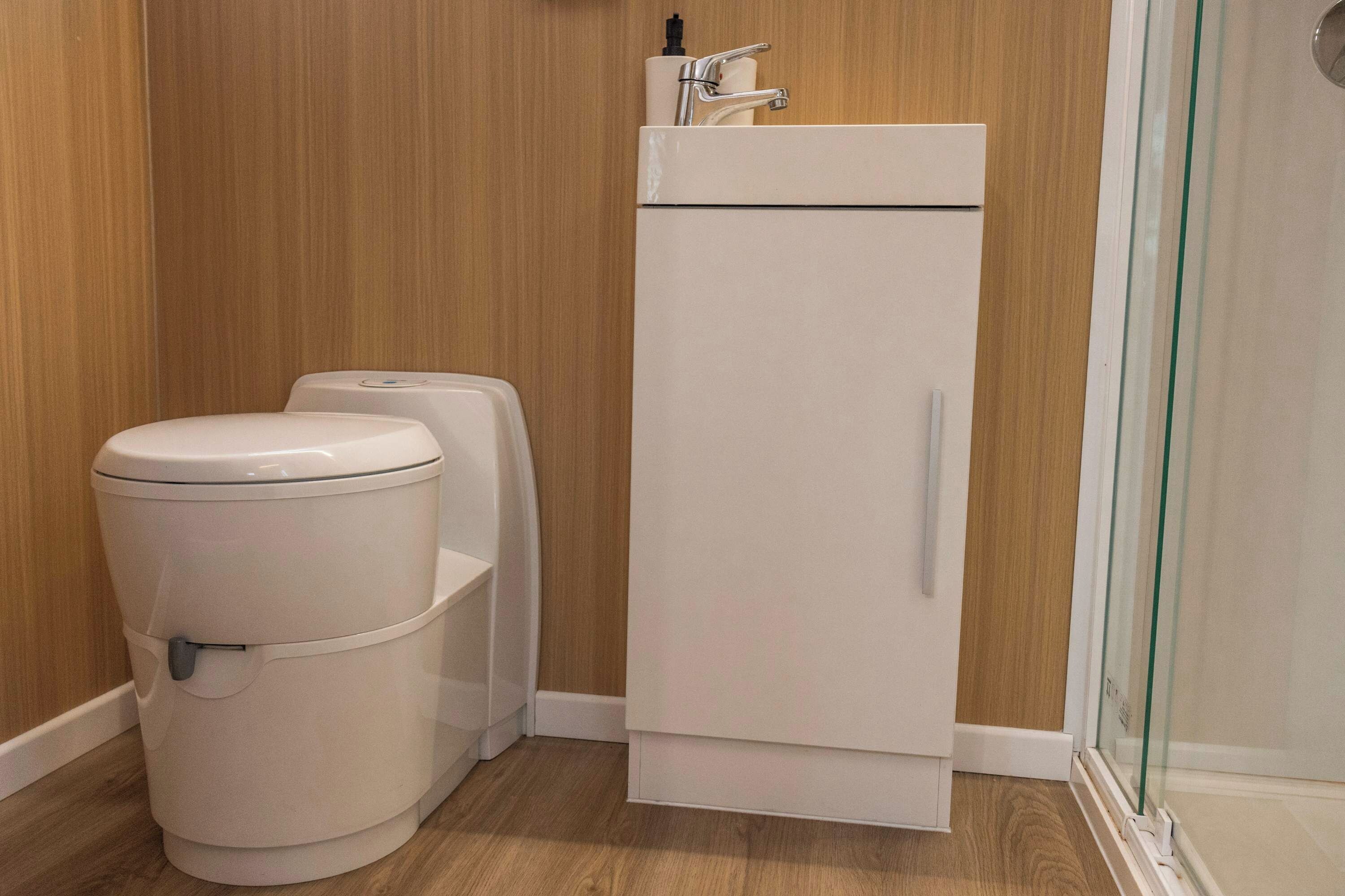 A compact bathroom with a toilet, bidet, and a white cabinet.