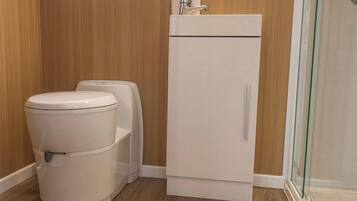 A compact bathroom with a toilet, bidet, and a white cabinet.