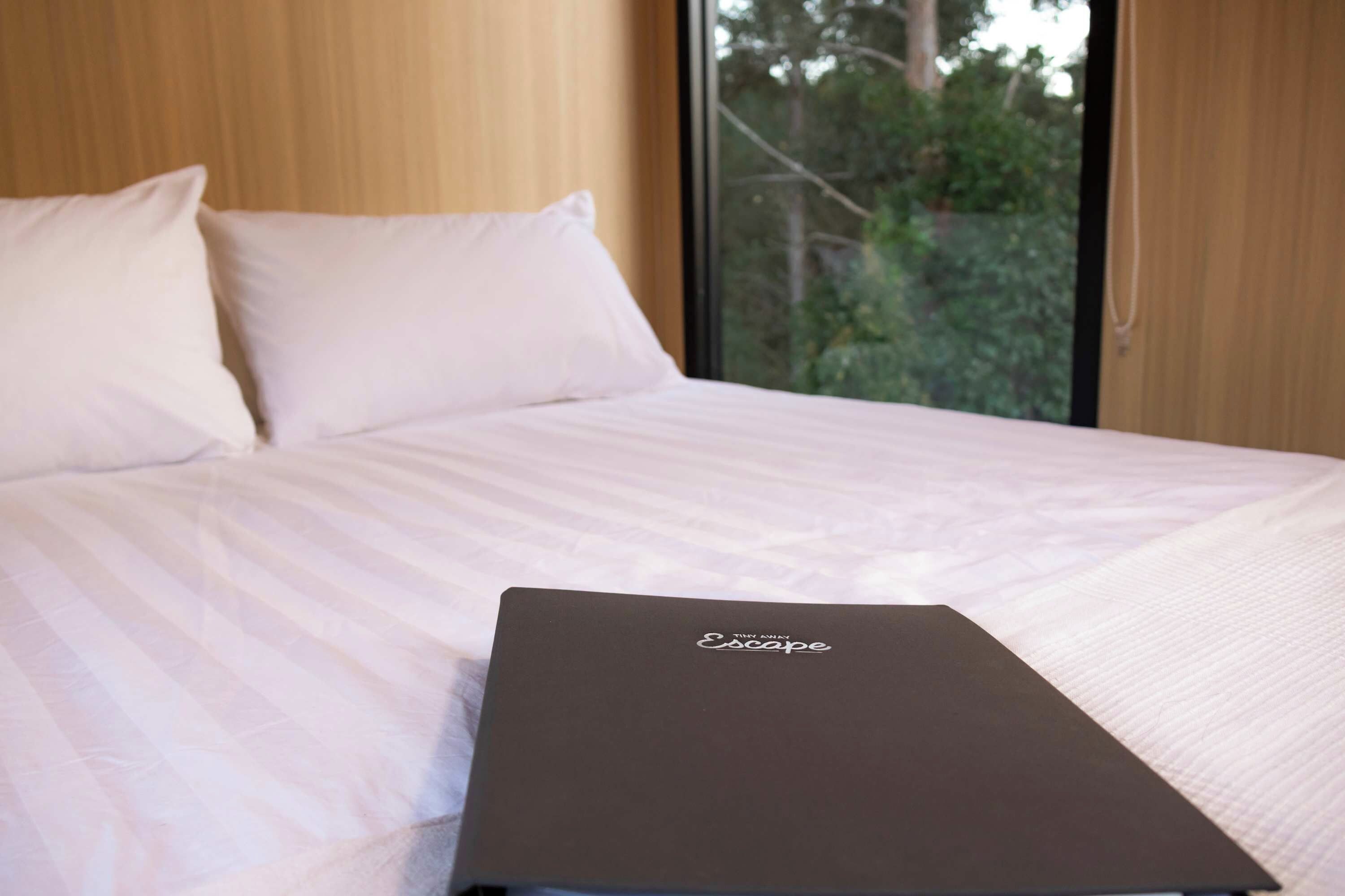 Een bed met witte lakens en een zwarte laptop erop.