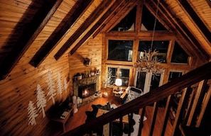 A wooden interior with a fireplace, wooden beams, and a chandelier.