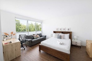 Une chambre moderne avec un grand lit, un bureau, une chaise et un canapé.