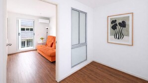A hallway with a sliding glass door leading to a living area with an orange sofa and a small table with a lamp. - Stylish 2BR Brunswick Home (Brunswick)