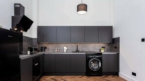 A modern kitchen with dark cabinetry, a built-in dishwasher, and a herringbone wood floor.