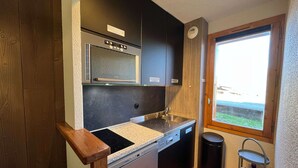 A compact kitchen with a built-in oven, a sink, and a window offering a view. - Newly renovated slopeside studio (Montchavin-les-coches)