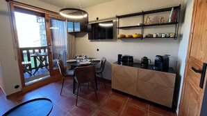 A compact kitchen with a dining area, a coffee maker, and a TV on the wall. - Newly renovated slopeside studio (Montchavin-les-coches)