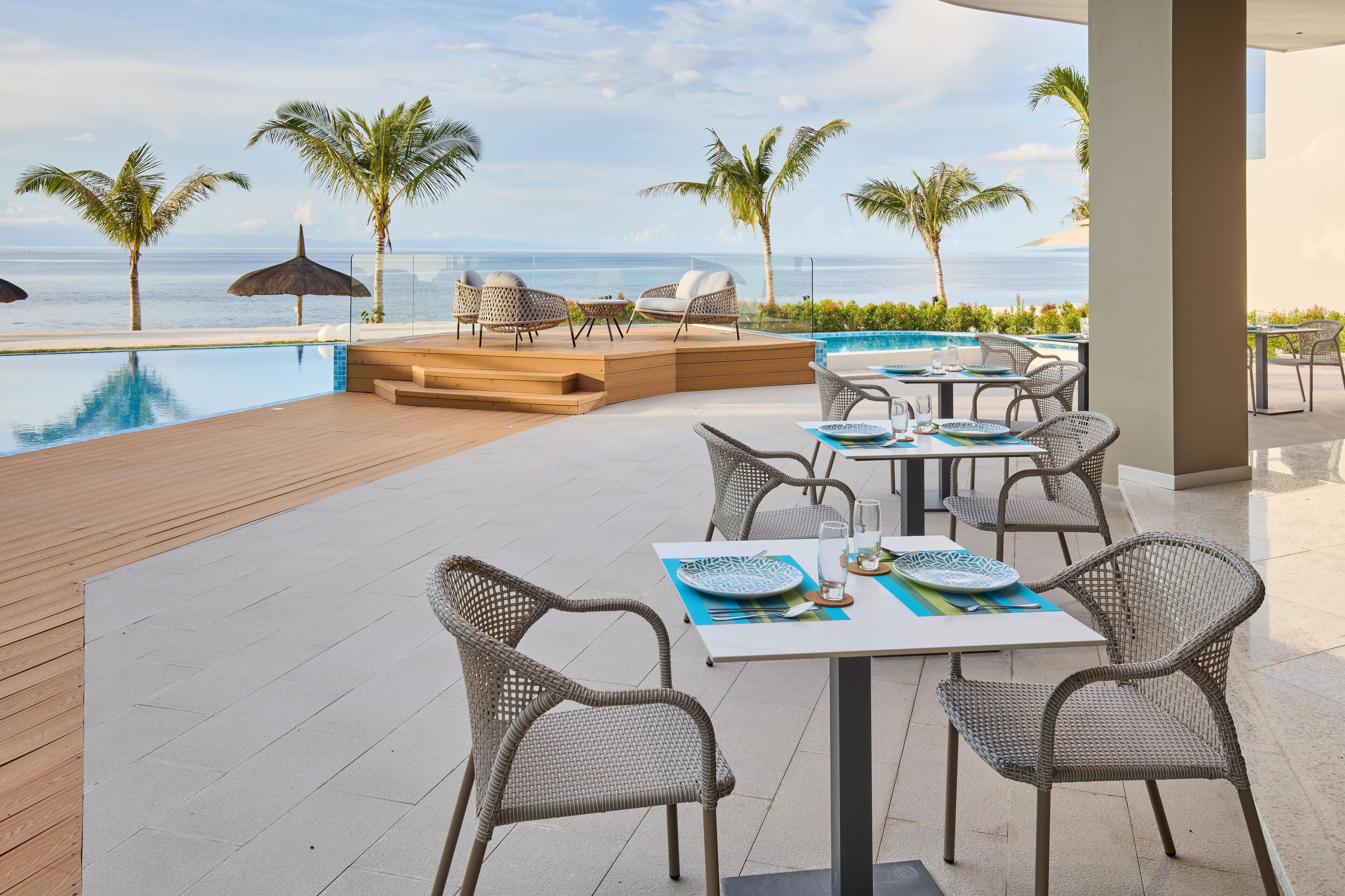 A poolside area with outdoor seating and a view of the ocean.