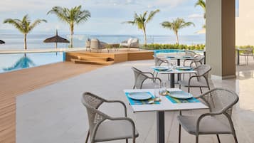 A poolside area with outdoor seating and a view of the ocean.