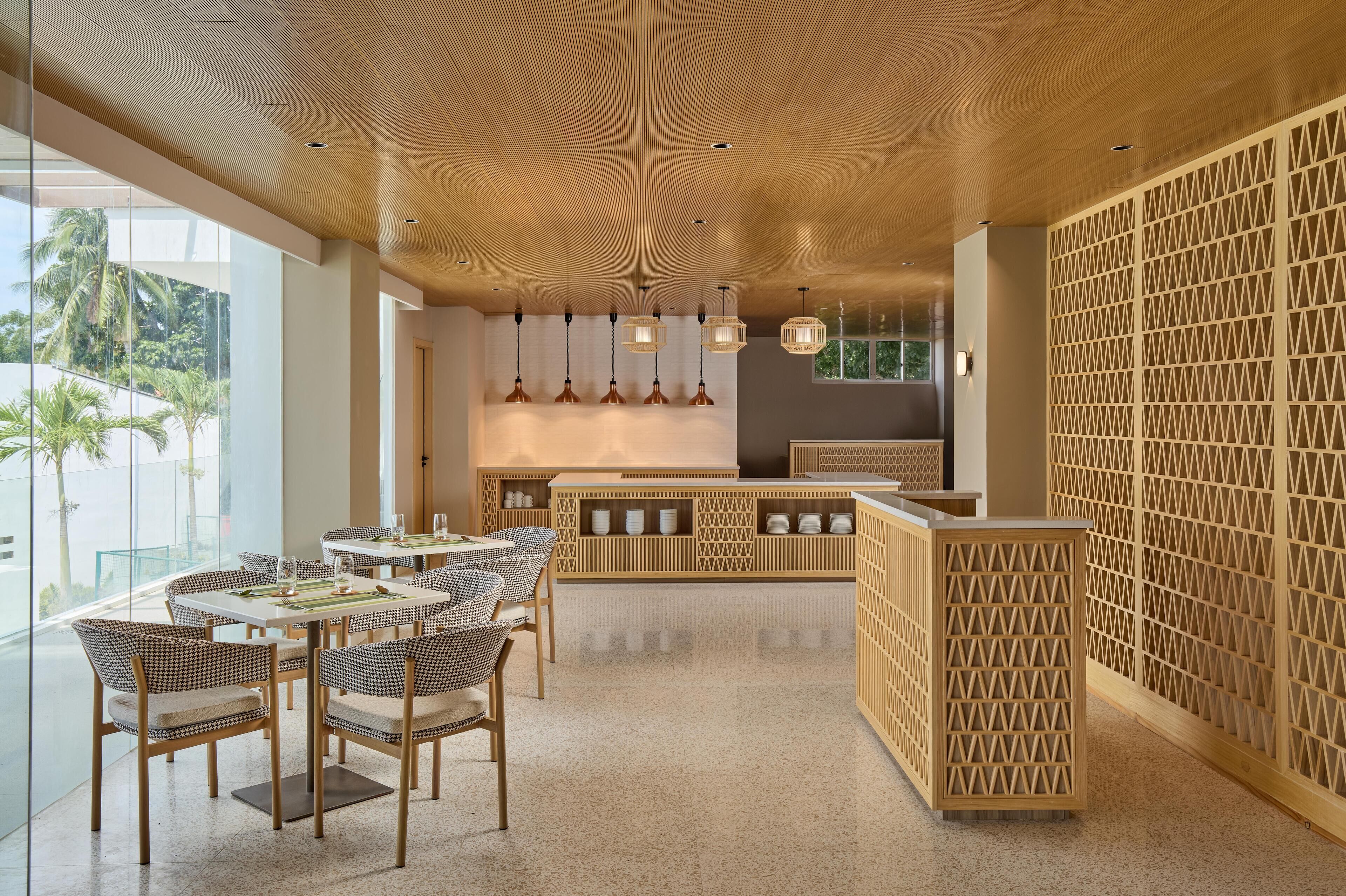 A modern interior with a wooden ceiling, a bar area, and a seating area with tables and chairs.