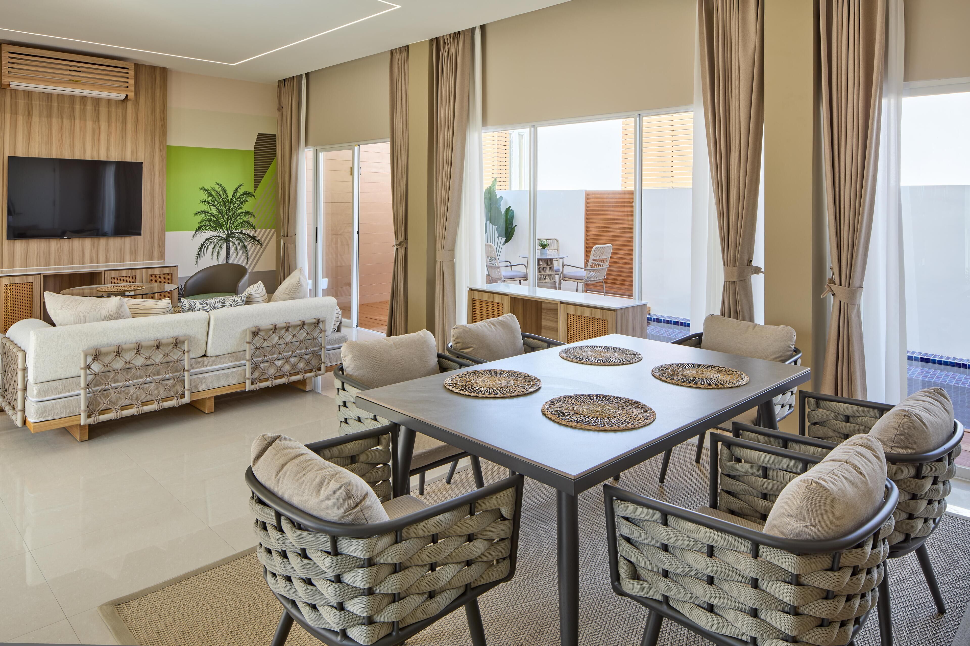 Una sala de estar moderna con sofá, televisor y comedor con sillas y una mesa.