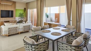 Una sala de estar moderna con sofá, televisor y comedor con sillas y una mesa.