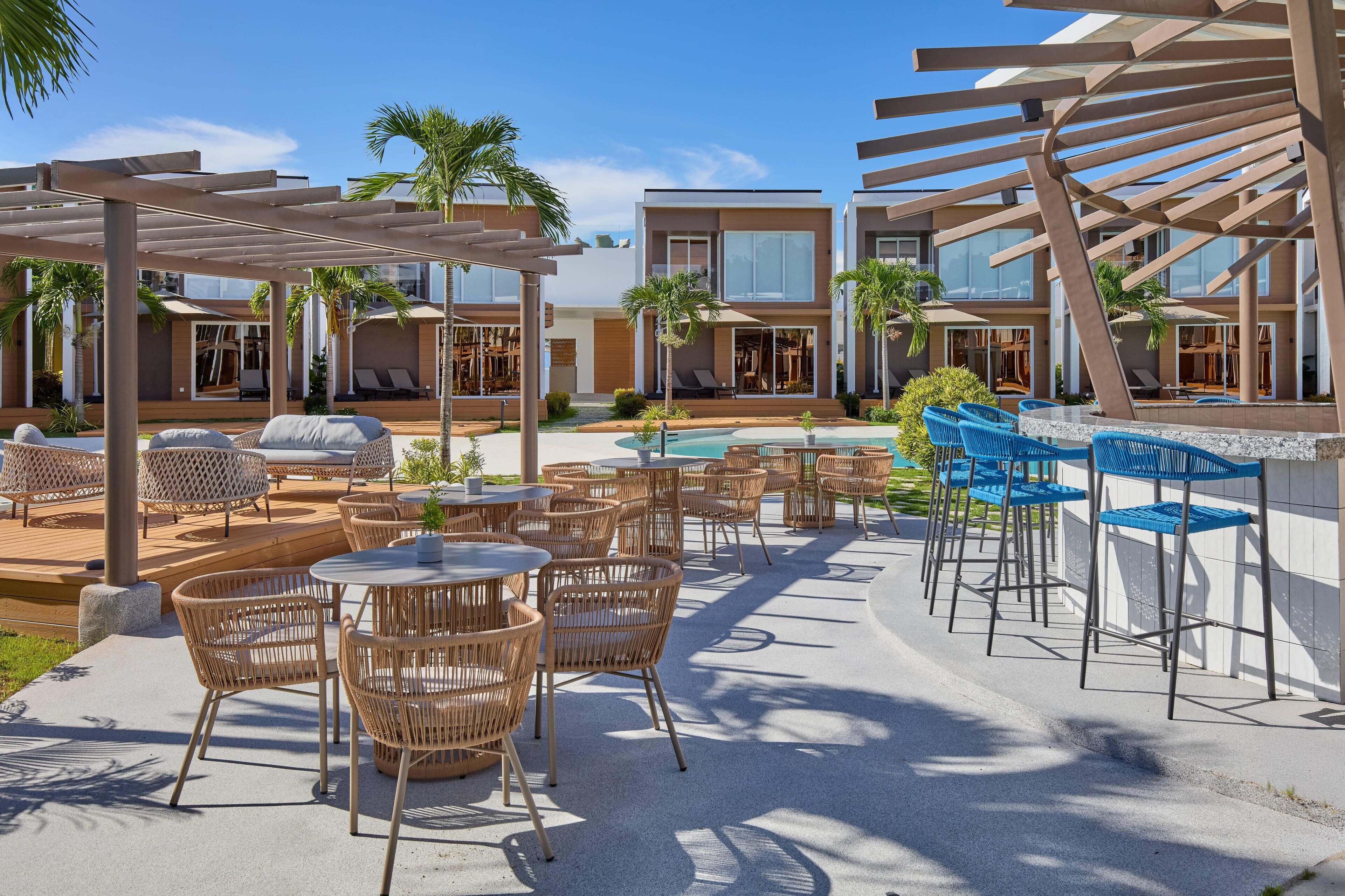A modern outdoor pool area with lounge chairs, tables, and a bar.