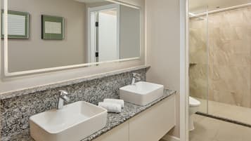 Un baño moderno con dos lavamanos, un espejo grande y una zona de ducha.