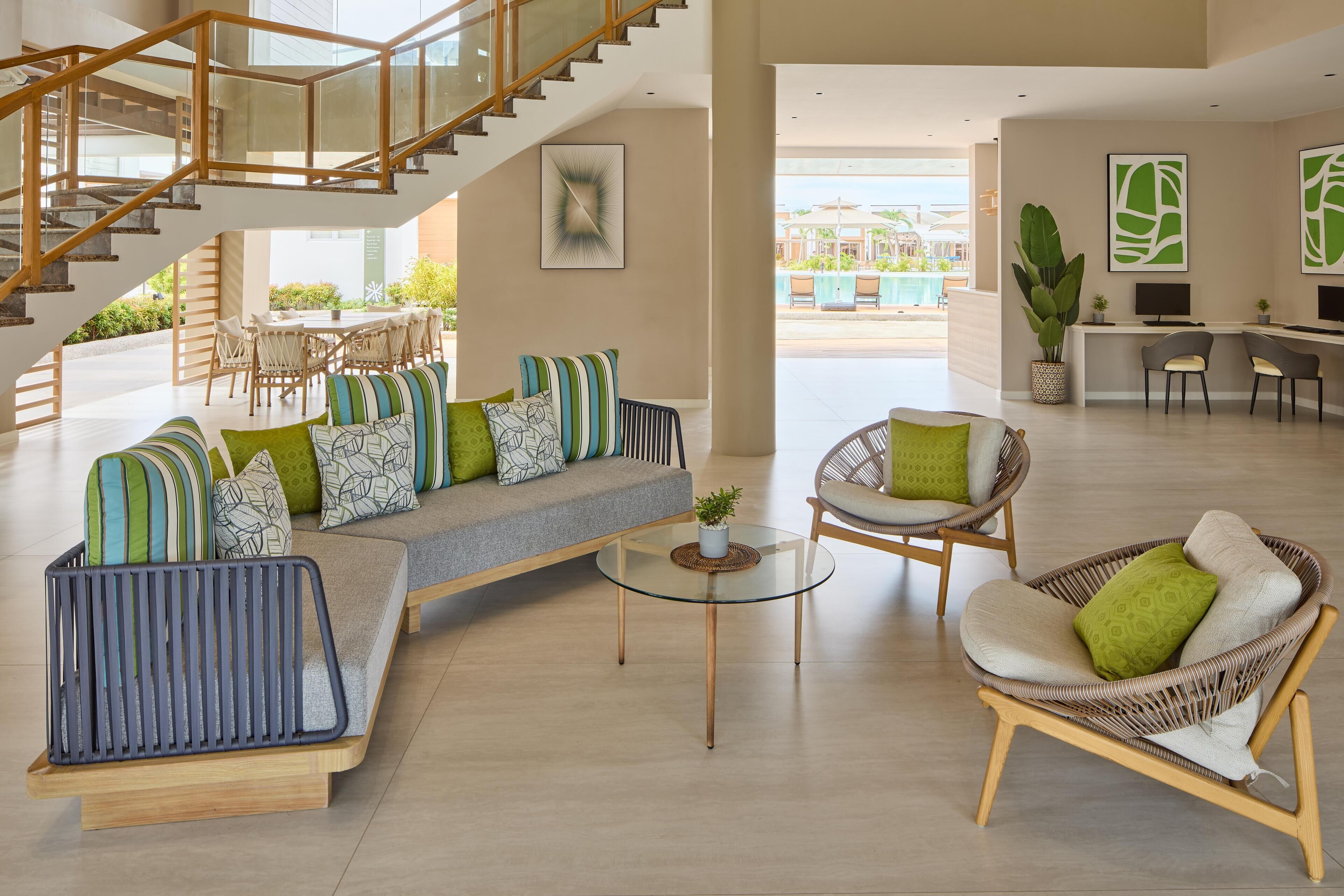 A spacious living area with a staircase, seating arrangements, and a reception desk.