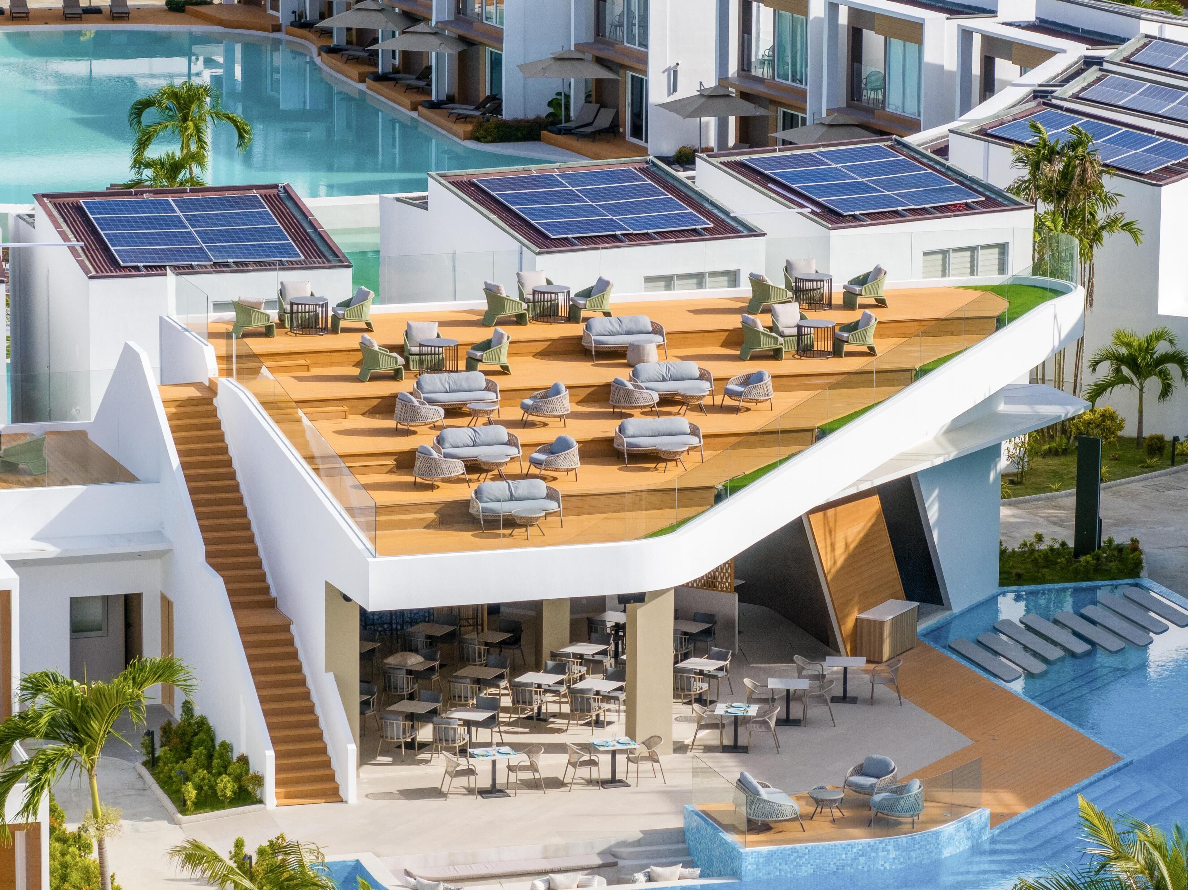Un complexe hôtelier moderne doté d’une piscine sur le toit, de panneaux solaires et d’un espace de détente extérieur.