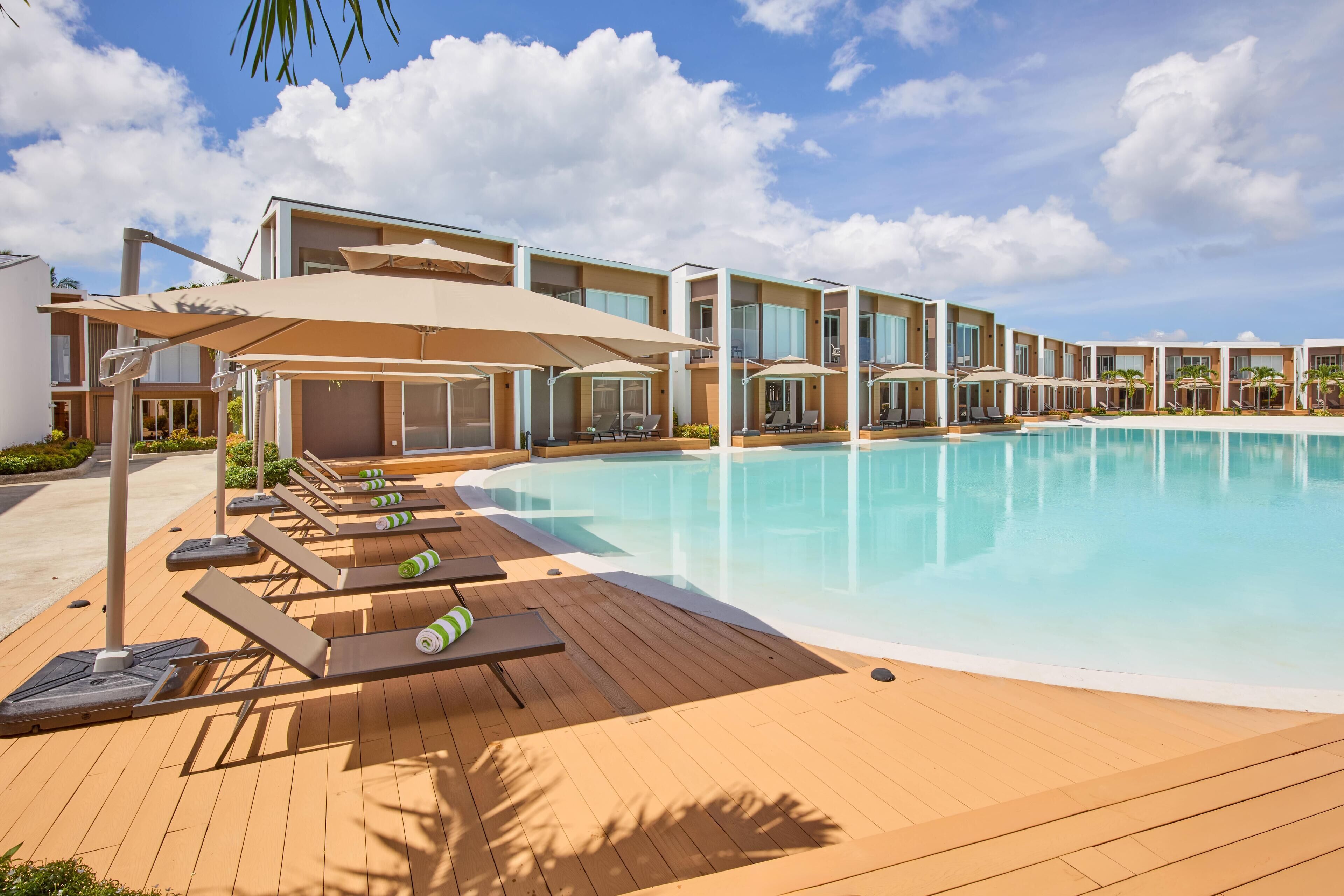 A poolside area with sun loungers, umbrellas, and a clear blue pool.