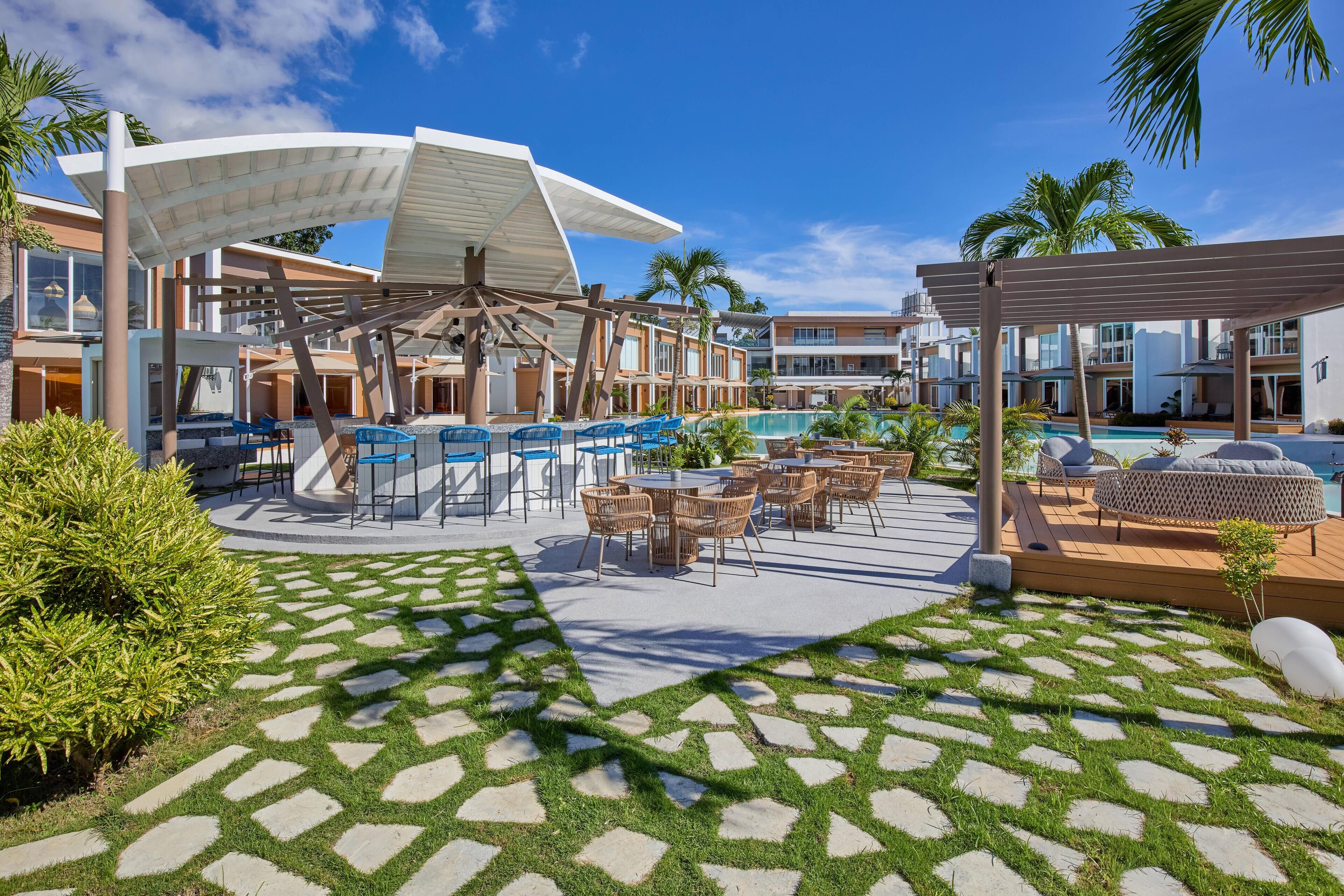 A pool area with lounge chairs, umbrellas, and a pool.