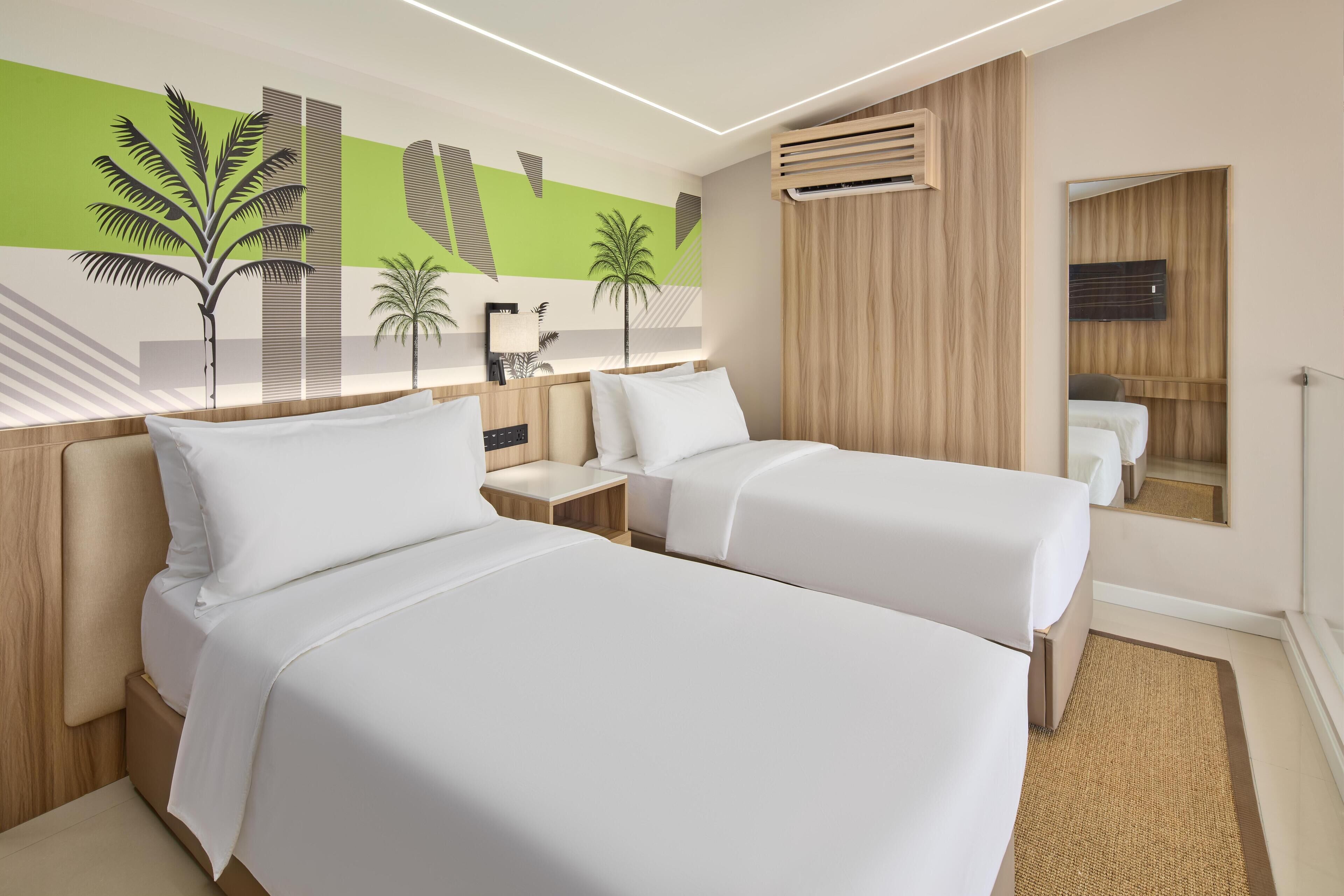 A hotel room with two beds, a large mirror, a wall-mounted air conditioner, and a decorative mural.
