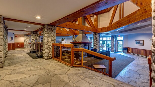 A spacious lobby with stone flooring, wooden beams, and a fireplace. - Lake Placid Lodge - Ski-In/Out, Pool, Hot Tub & Sauna, No Stairs (Whistler)