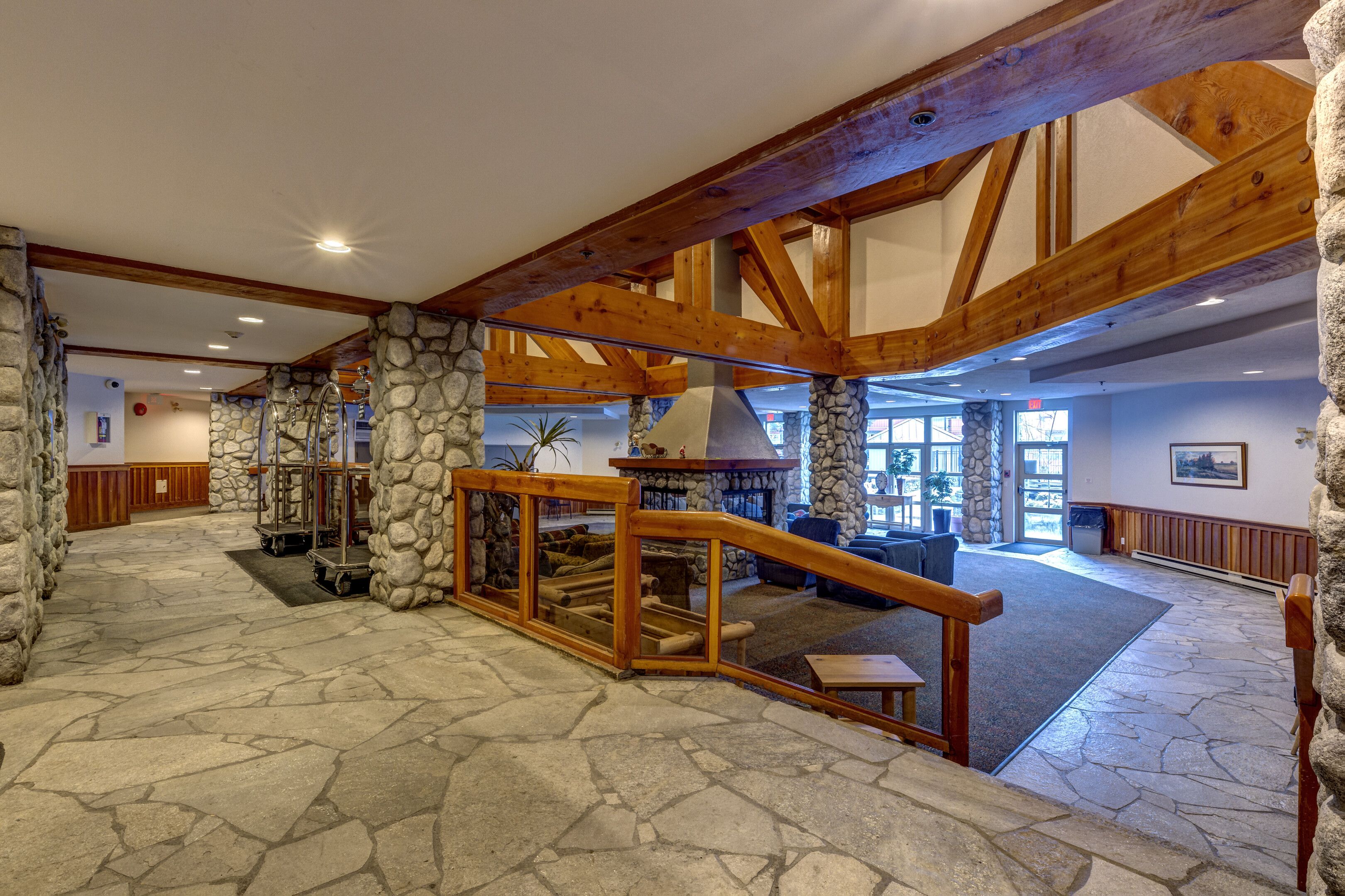 A spacious lobby with stone flooring, wooden beams, and a fireplace.