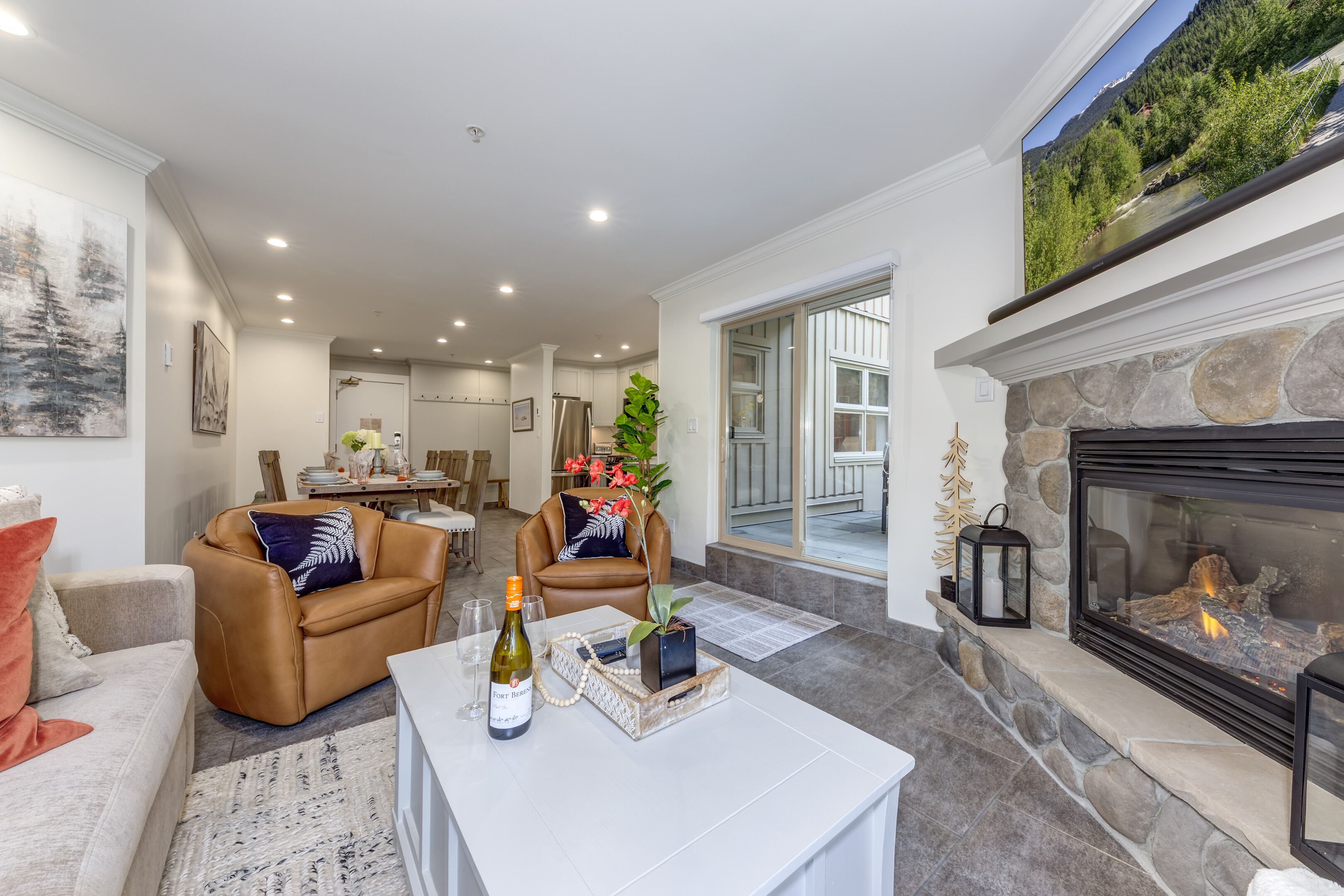 A modern living room with a fireplace, a dining area, and a view of a mountain landscape.