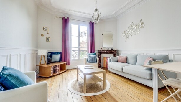 Una sala de estar con televisor, sofá y mesa de comedor.