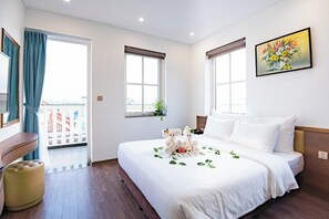 A hotel room with a large bed, a small seating area, and a balcony with a view. - Indotel Ha Long Hotel (Ha Long)