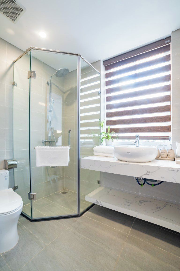 A modern bathroom with a glass-enclosed shower, a white sink, and a vanity with a mirror.