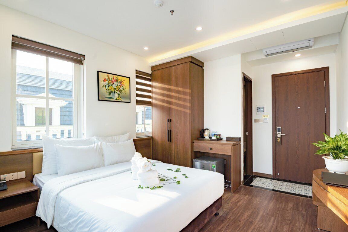 A hotel room with a bed, a wardrobe, a desk, and a window.