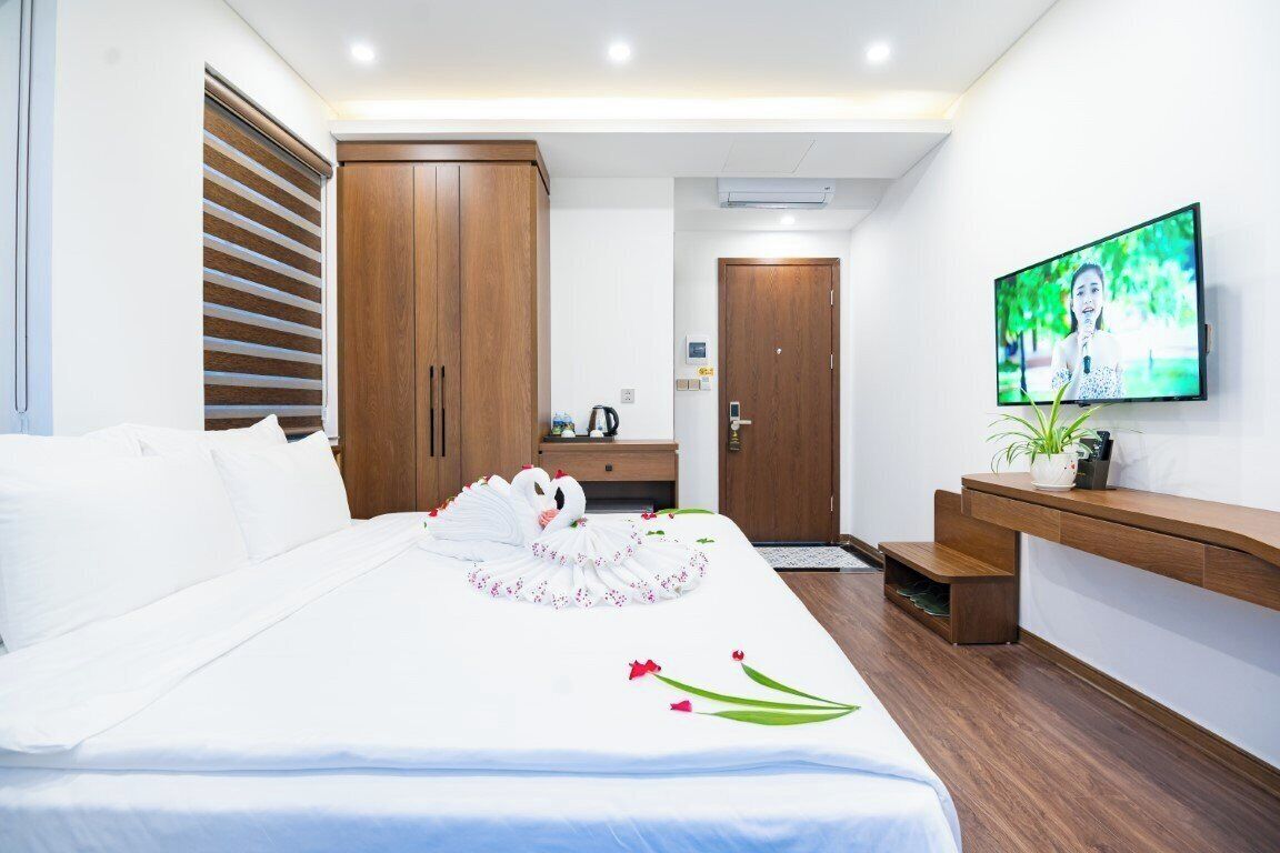 Une chambre d’hôtel avec un grand lit, une armoire en bois, une télévision et un petit bureau.