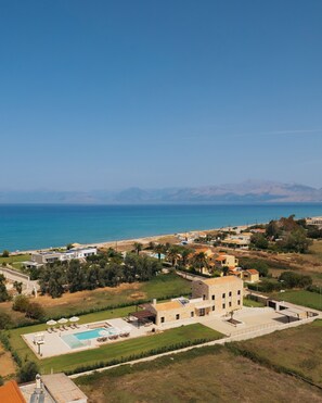 A residential area with a swimming pool, houses, and a view of the sea.