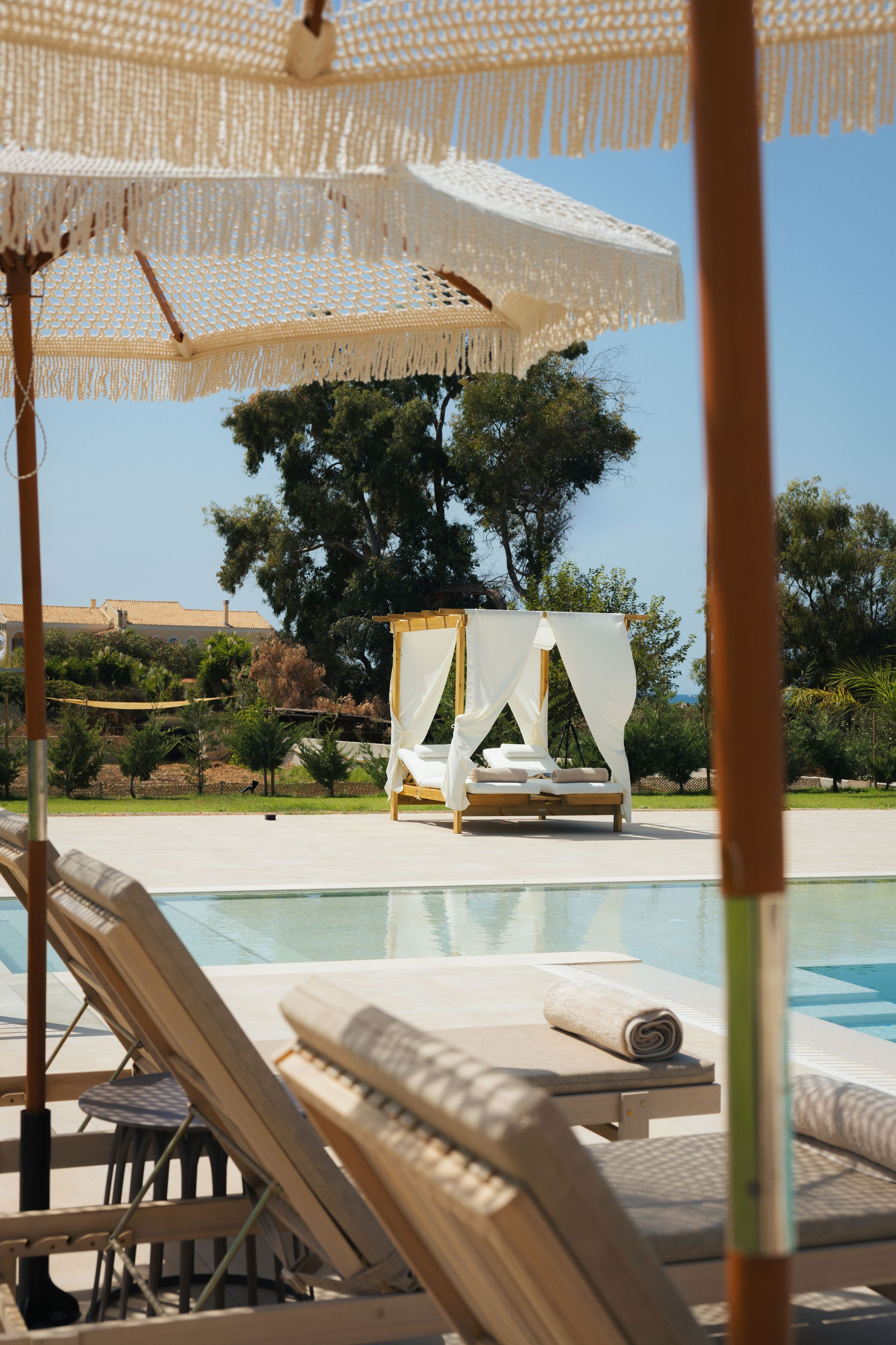 Un espace aménagé au bord de la piscine, avec des chaises longues, un auvent et un lit à baldaquin.