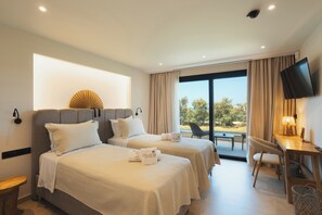 A hotel room with two beds, a desk, a chair, a TV, and a view of the outdoors.