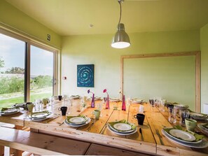 Een eettafel gedekt met borden, glazen en bestek, met een hanglamp erboven.