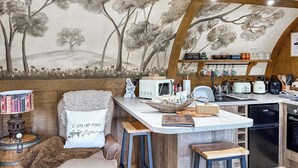 A cozy kitchen with a mural of trees, wooden beams, and a bar area with stools.