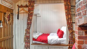 Una habitación acogedora con una cama individual, un armario de madera y una pared de ladrillo.