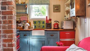 Una cocina con armarios azules, un refrigerador rojo y una ventana con vistas al verdor.