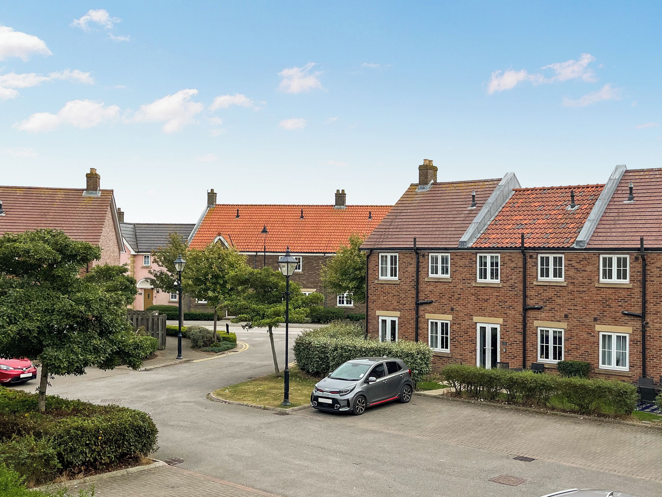 A residential street with houses, a parked car, and a clear sky.