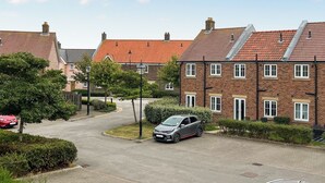 A residential street with houses, a parked car, and a clear sky. - 1 bedroom accommodation in Filey (Filey)