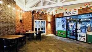 A café with a brick wall, wooden tables, and chairs. There's a shop with a rainbow flag banner and a sign that reads 'The Four Cats'. - 1 bedroom accommodation in Filey (Filey)