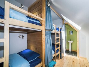 Een slaapzaal met stapelbedden, een trapje, een wastafel en een dakraam.