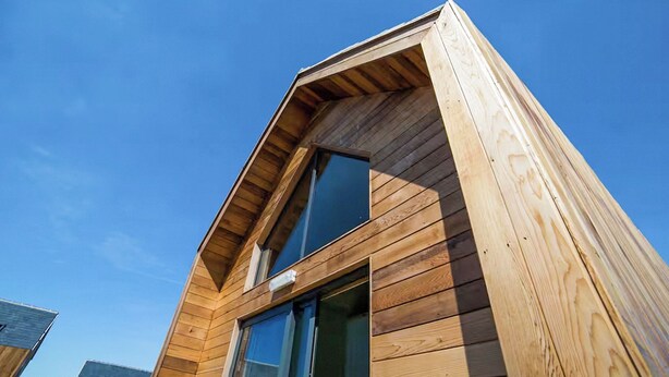 Eine moderne Holzdiele mit Satteldach und großen Fenstern.
