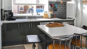 Una cucina moderna con un'ampia finestra, piano cottura integrato e zona pranzo con due sedie.